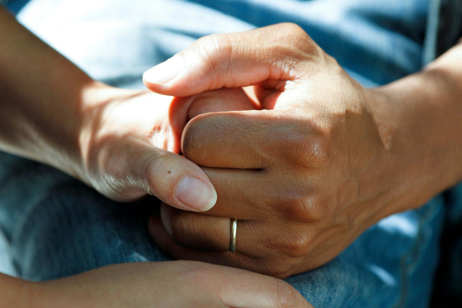 Two pairs of hands gently clasped, an older and a younger person, conveying care and connection